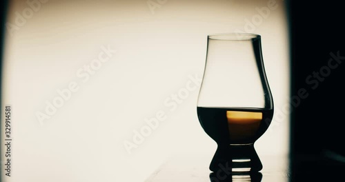 4K footage of a person putting  a Glencairn whisky glass on a table, backlit.