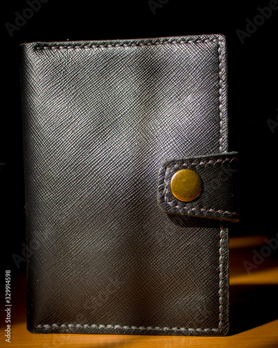 handmade black leather wallet located on a wooden board