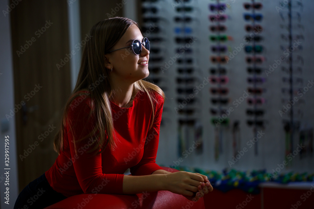 Beautiful young girl chooses sunglasses in an optics store. Beautiful young girl chooses sunglasses in an optics store.