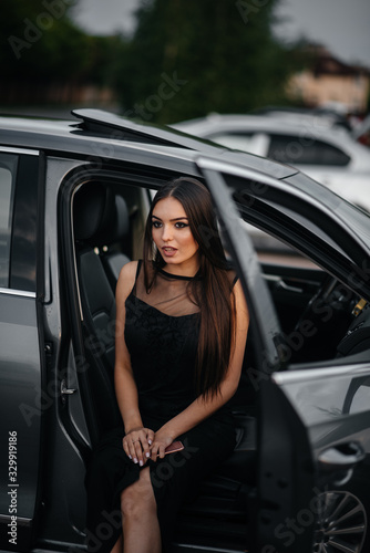 Stylish young girl sitting in a business class car in a black dress. Business fashion and style © Andrii