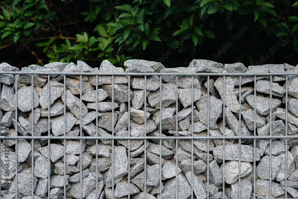 A beautiful textured fence made of mesh and stones. Background.