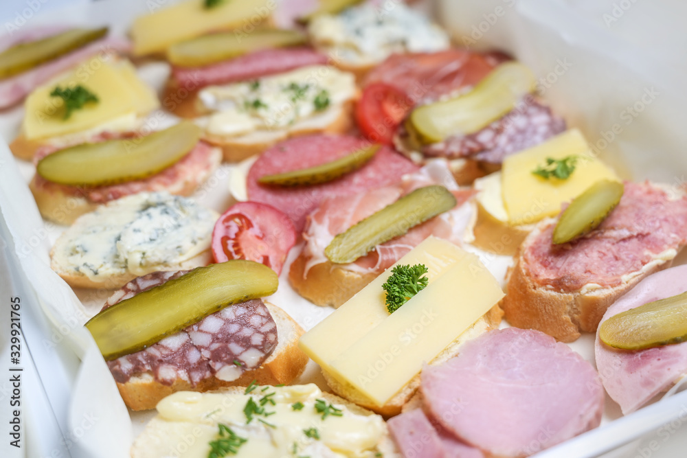 baguette canapes with cheese, ham and sausage, garnish from tomatoes, gherkins and herbs for a casual party baguette canapes with cheese, ham and sausage, garnish from tomatoes, gherkins and herbs for a casual party