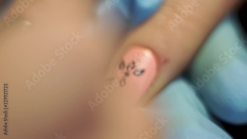 Application of black design on the pink nails of the client in the office for manicure. Close-Up