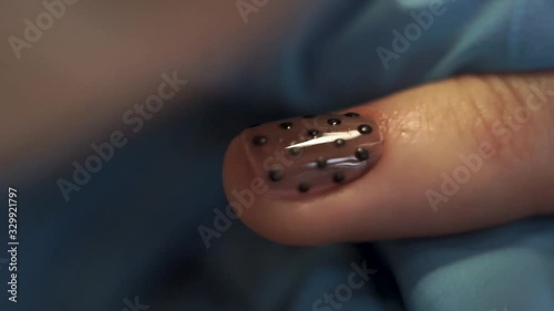 Manicurist wipes a nail after applying the design. Extra Close-Up