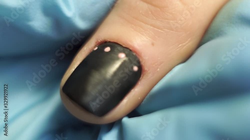 Manicurist draws pink dots on the client’s black nail