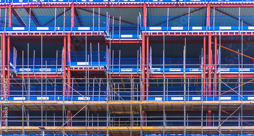 Scaffolding wall. Construction workers working on scaffolding with safety net. Background of construction wall on site. Building Construction. New house development under construction. Safety scaffold