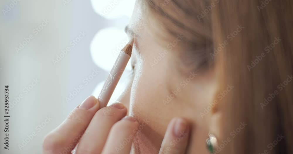 Makeup artist adjusts the eyebrow line with a pencil Makeup artist adjusts the eyebrow line with a pencil