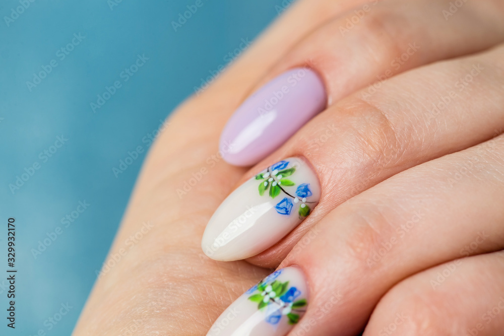 Nails Design. Hands With Bright lilac and White Manicure with Spring flowers. Close Up Of Female Hands. Art Nail. Nails Design. Hands With Bright lilac and White Manicure with Spring flowers. Close Up Of Female Hands. Art Nail.