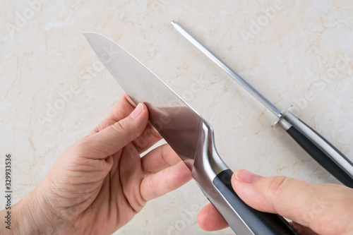 Принти на полотні Woman hands checking the blade of professional chef knife after using the sharpening steel