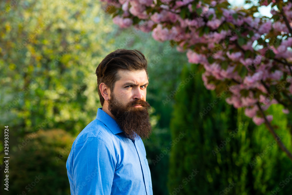 Handsome young man on spring nature background looking at camera. Male model Enjoying Nature. Romantic beauty in fantasy orchard. Handsome young man on spring nature background looking at camera. Male model Enjoying Nature. Romantic beauty in fantasy orchard.