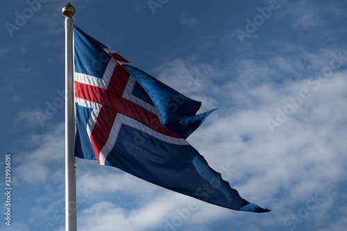 Icelandic flag in the wind on blue sky with clouds