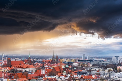 Heavy storm black storm clouds over the city. Rainy weather and red roofs of houses