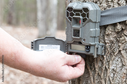 A man taking the SD card out of a motion activated trail camera to check the photos for wild game. Trail cameras are often used by hunters and wildlife enthusiasts to survey the animals in the area.