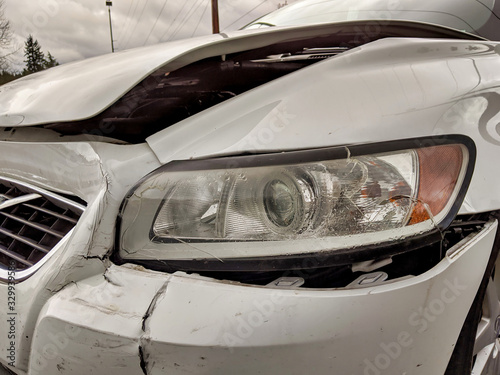damage to the front bumper and headlight of a white car © ColleenMichaels