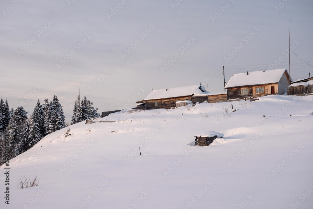Winter landscape. Exterior view of wooden houses covered with snow in Russian village located in Siberia. Russia.