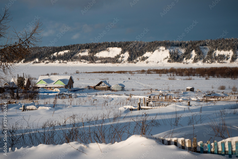 Winter landscape. Exterior view of wooden houses covered with snow in Russian village located in Siberia. Russia.