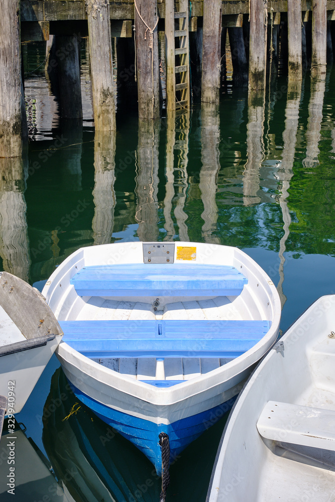 Docked small rowboats and skiffs tied together on a calm and peaceful Coastal Maine dock and Harbor Docked small rowboats and skiffs tied together on a calm and peaceful Coastal Maine dock and Harbor