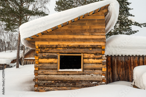 Winter landscape. Exterior view of wooden house covered with snow in Russian village located in Siberia. Russia. photo