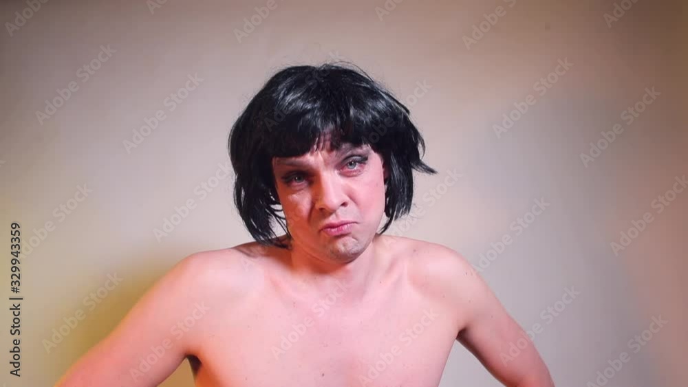 A male blogger with painted eyes and long hair is talking to subscribers. Holding a cat in his hands. Hand closes the lens. Video blogger concept. A male blogger with painted eyes and long hair is talking to subscribers. Holding a cat in his hands. Hand closes the lens. Video blogger concept.