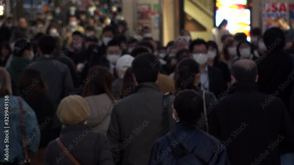 TOKYO, JAPAN - MARCH 2020 : Crowd of people at the street near Shinjuku station in rush hour. Commuters and tourists wearing surgical mask to protect from Coronavirus(COVID-19) or cold. Slow motion. TOKYO, JAPAN - MARCH 2020 : Crowd of people at the street near Shinjuku station in rush hour. Commuters and tourists wearing surgical mask to protect from Coronavirus(COVID-19) or cold. Slow motion.