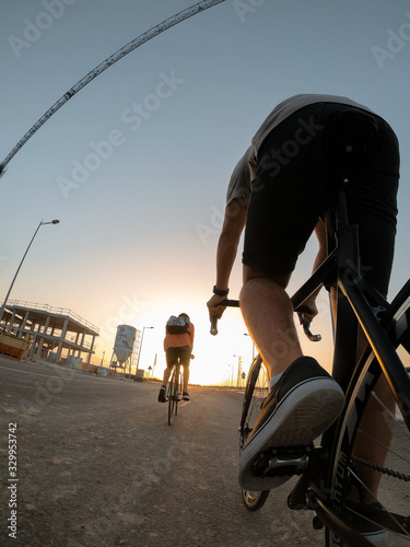 Close up young boys ride bicycles through the city of Seville, sunset.