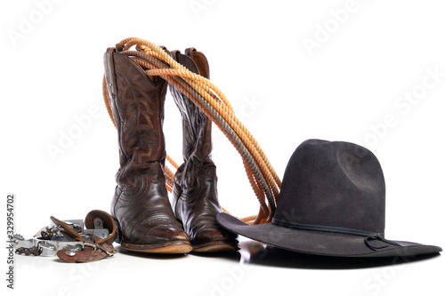 Slika na platnu Western boots and a lap or lariat rope and spurs and a cowboy hat on a white bac