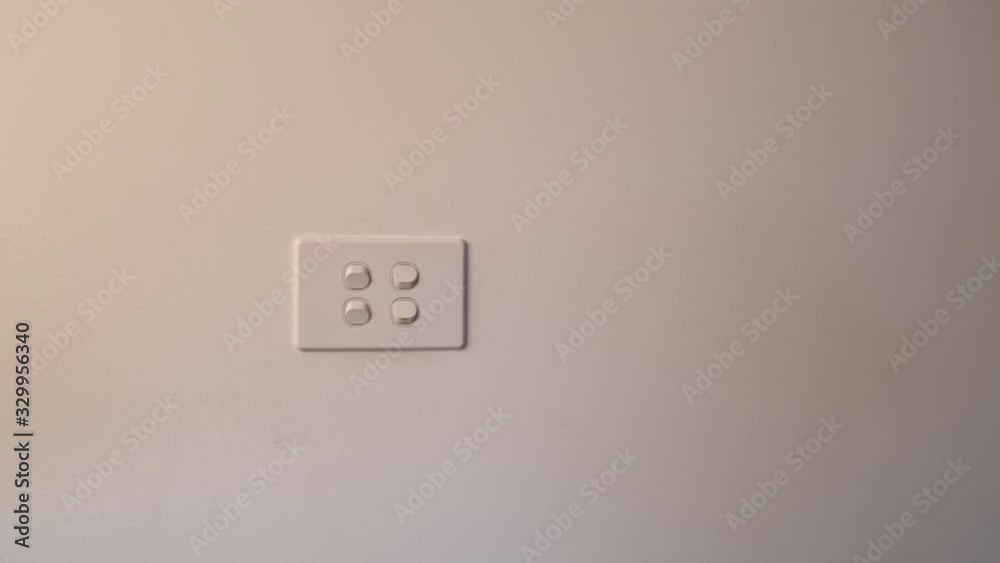 Woman hand turning on two white light switches on a wall Woman hand turning on two white light switches on a wall