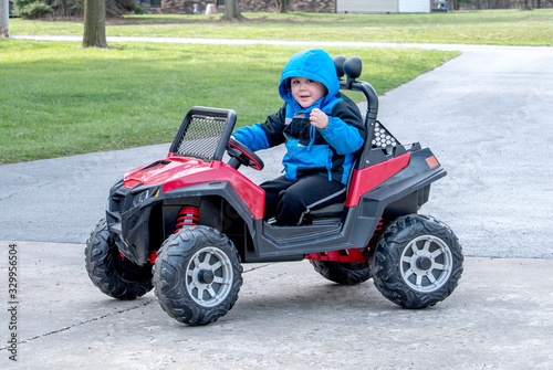 a cute little boy poses as he drives a battery powered jeep