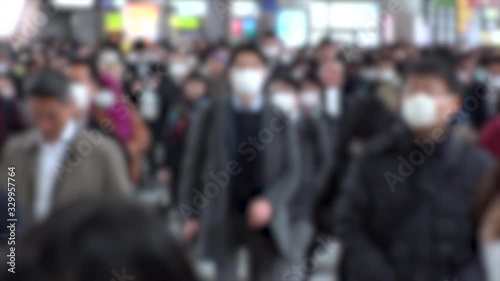 TOKYO, JAPAN - MARCH 2020 : Crowd of people walking at Shinagawa station in morning rush hour. Commuters going to work. People wearing mask to protect from Coronavirus(COVID-19). Blurred slow motion. photo