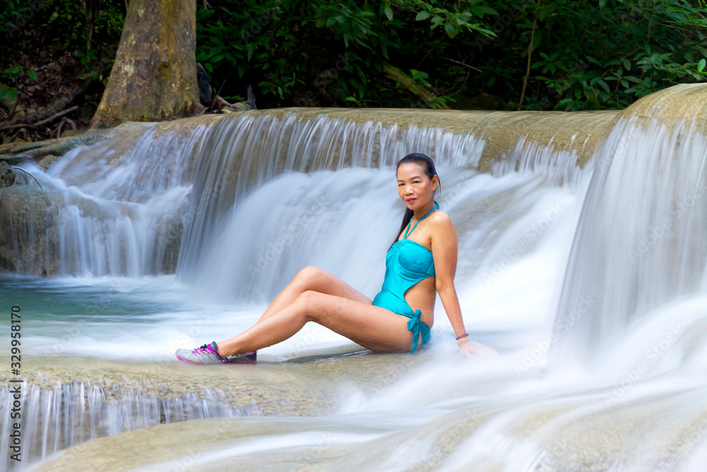 Woman with blue swimsuit happy at Erawan Waterfall and natural