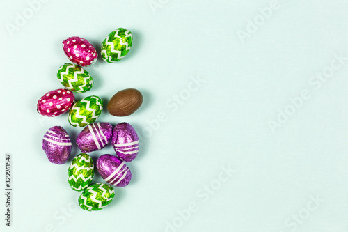 Colorful chocolate easter eggs on blue background. Small Chocolate eggs in a foil. Traditional Easter sweet. Copy Space
