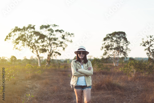 Portrait of traveler asian woman standing and cross arm on sunset time in the forest,Happy and smiling,Relaxing time