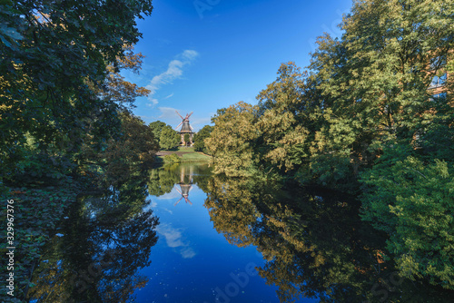 Wallanlagen Park in a sunny day, old wooden windmill with river in front, Bremen, Germany