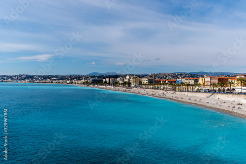 Panoramic wide angle shot of the Quai des États-Unis, people relaxing on the beach of the Mediterranean Sea coastline with the sunlight reflecting in the turquoise water (Nice, France) © k.dei