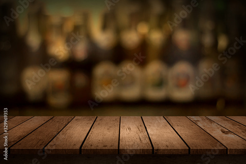 Wooden table with a view of blurred beverages bar bottle background. For create montage product display.