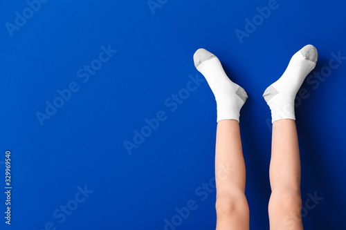 Legs of little girl in socks on color background