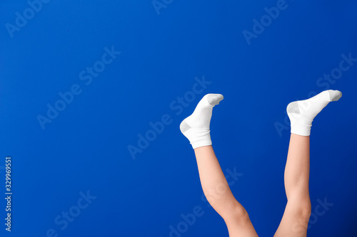 Fototapeta Naklejka Na Ścianę i Meble -  Legs of little girl in socks on color background