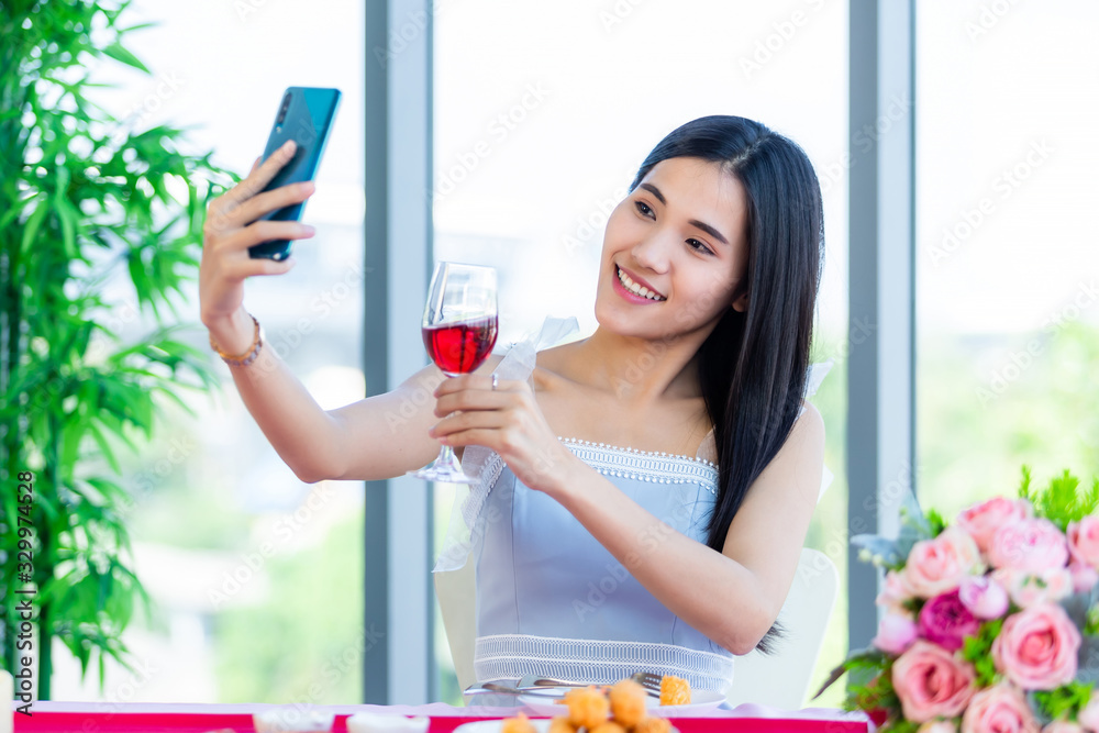 Valentine's day concept,Selfie of Happy of smiling Asian young female sitting at a table food holding with wine glasses at in the restaurant background Valentine's day concept,Selfie of Happy of smiling Asian young female sitting at a table food holding with wine glasses at in the restaurant background