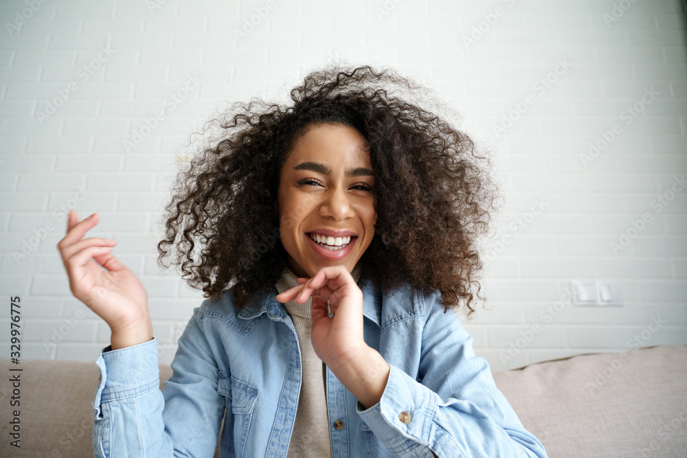 Cheerful african teenage girl blogger talking to camera recording vlog.  Happy mixed race young woman laughing making video call at home. Funny  social media influencer streaming blog. Webcam view. Stock Photo