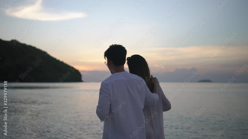 Young people taking evening walk by the sea, young man holding wine glass in one hand and hugging his girlfriend with another slow motion