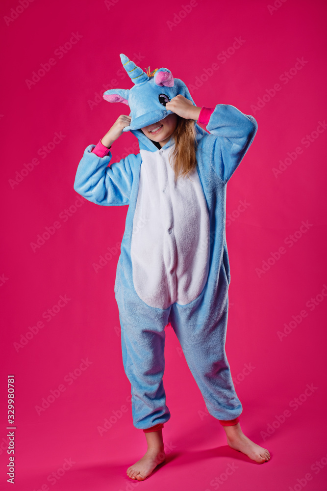 Charming girl playfully poses in the costume of the unicorn. Studio shot of  an emotional woman in kigurumi having fun on a pink background. Photos |  Adobe Stock