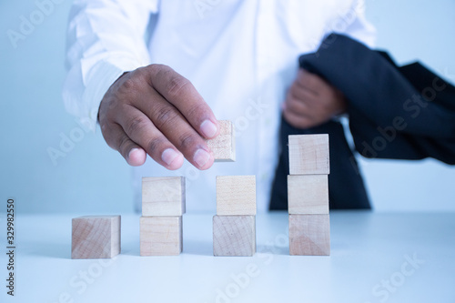 Businessman Wooden cubes on a desk in the office, Concept: Business to succeed that challenges teamwork,  design development strategy investment, symbol Financial advisor shows  to asset growth