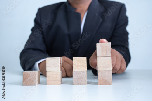 Businessman Wooden cubes on a desk in the office, Concept: Business to succeed that challenges teamwork, design development strategy investment, symbol Financial advisor shows to asset growth