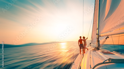 Young couple enjoys sailing in the tropical sea at sunset on their yacht. Motion blurred image