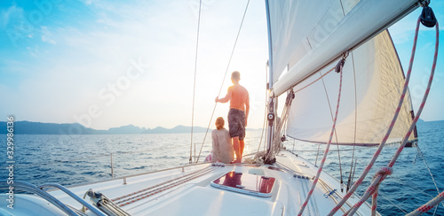 Young couple sailing in the tropical sea at sunset on their yacht © Dudarev Mikhail