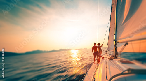 Young couple enjoys sailing in the tropical sea at sunset on their yacht. Motion blurred image © Dudarev Mikhail