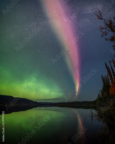 Aurora Borealis Northern Lights seen outside of Whitehorse, Yukon Territory Canada during fall, autumn with bright green band seen along river with reflection in water below. Wallpaper, desktop © Scalia Media