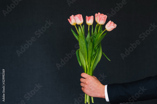 man's hand giving bouquet of pink tulips