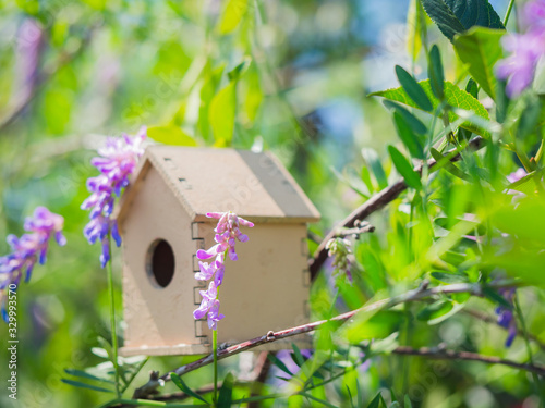 Cute wooden toy bird house in the cute violet blue flowers