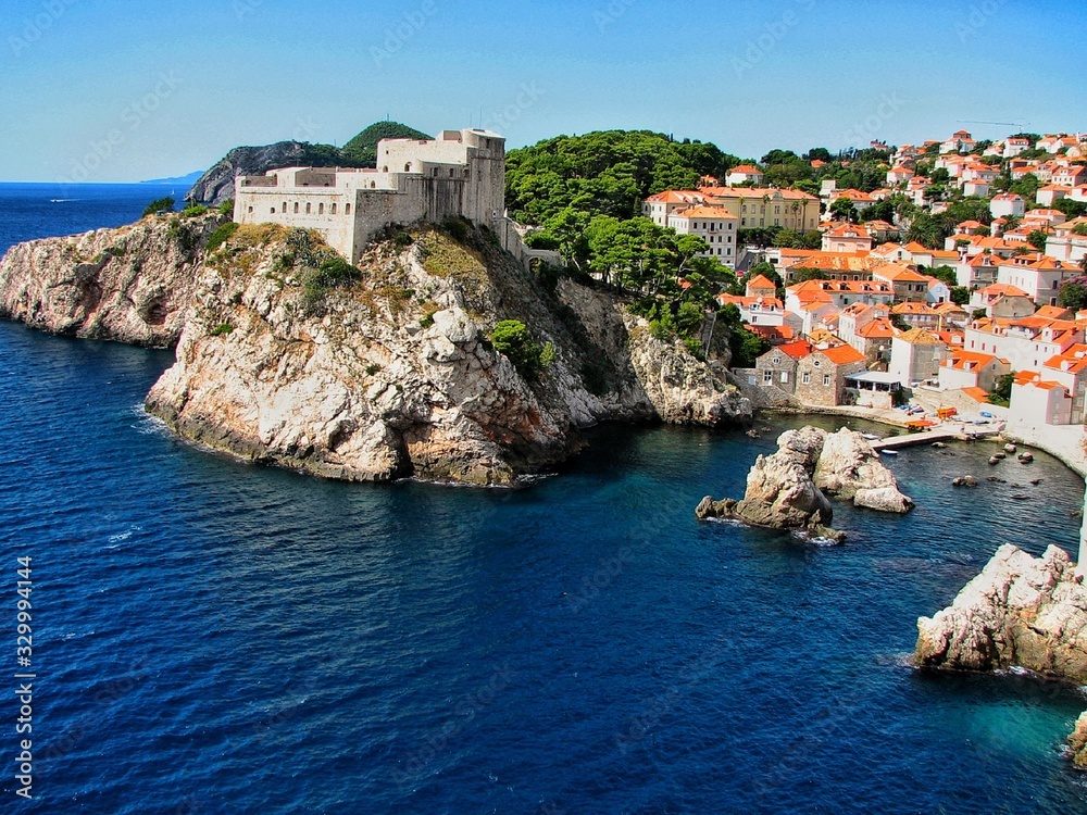 old fortress on a rock and part of the city of Dubrovnik on a sunny clear day, blue sea washes the coast, Montenegro